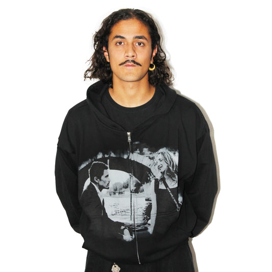 Before Sunset black zip hoodie, front view with faded black-and-white print of a couple under a stone bridge